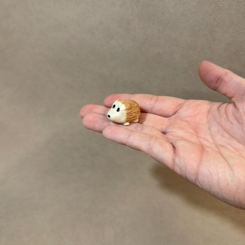 A miniature ceramic hedgehog, small enough to sit in the palm of a hand.